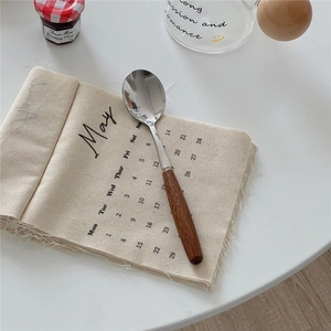 Close-up of a vintage spoon with a wooden handle next to a May fabric calendar