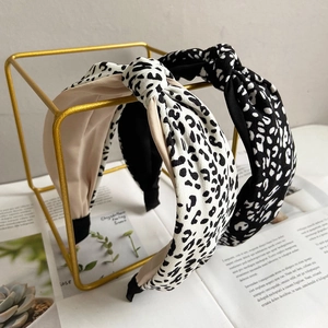 Stylish leopard print knotted headbands in beige and black displayed on a gold metal stand