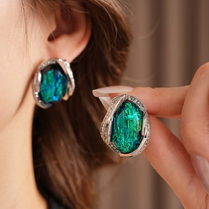 Detailed view of vintage resin earrings with large blue and green gemstones and crystals