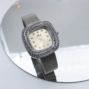 Macro detail of square silver watch with mesh band and double row of crystal accents