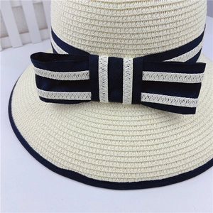 Women's straw boater hat with navy ribbon and striped bow for sun protection