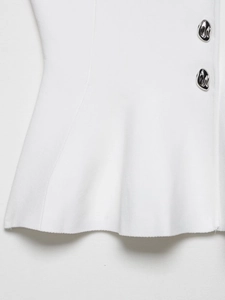 Close-up of white knitted fabric with silver metal buttons and pleated ruffle hem detail