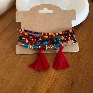 Detail of bohemian layered beaded bracelet featuring vibrant red tassels and crystal beads