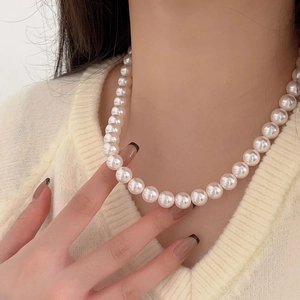 Elegant 10mm white pearl necklace on model wearing a soft cream V-neck knit sweater