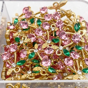 Detailed macro view of cherry pendants with pink rhinestones and gold metal in a clear box