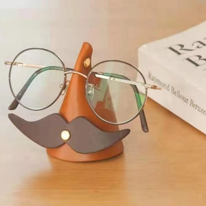 Close-up of a creative nose-shaped leather glasses holder with retro mustache and gold rivets