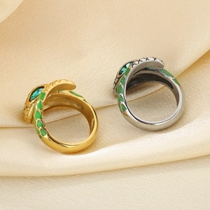 Detail of gold and silver snake rings with green enamel scales on champagne satin fabric