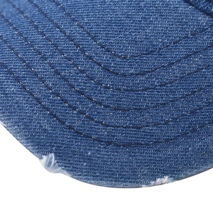 Close-up of washed denim baseball cap featuring distressed edges and neat curved stitching