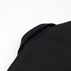 Close-up of black blazer lapel with fine twill texture and sharp tailored details