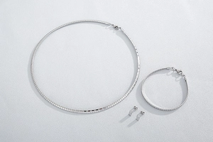 Detailed flat lay of silver flexible mesh chain necklace, bracelet, and stud earrings set