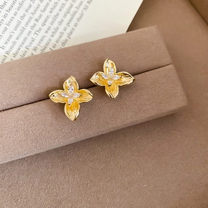Macro detail of gold flower earrings with marquise-cut zircons on a velvet jewelry box