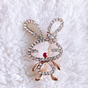 Detailed close-up of a golden rabbit brooch with sparkling rhinestones on white faux fur