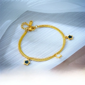Detail of double-layer gold star bracelet with black and white enamel star pendants