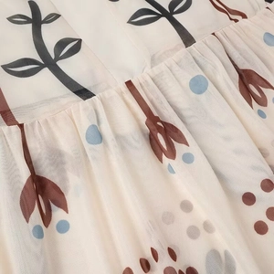 Close-up of beige mesh fabric with brown leaf prints and blue polka dots detailing