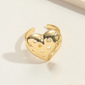 Macro shot of gold adjustable open ring featuring hollow heart patterns on textured surface