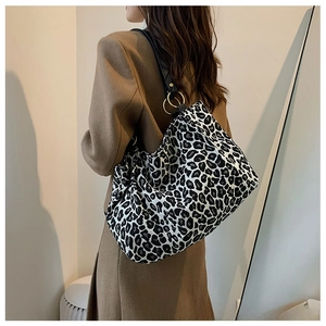 Detail of leopard print canvas tote bag featuring black leather strap and gold ring hardware