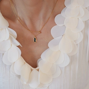 Détail d'un collier doré double épaisseur avec pendentif ovale noir et petites perles