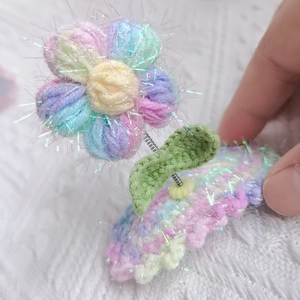 Detail of handmade knit flower hair clip with macaron yarn and sequin embellishments