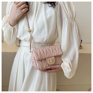 Close-up of pink quilted mini bag with gold chain strap and metal turn-lock closure