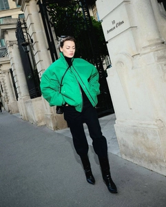 Street style view of oversized green bomber jacket paired with black boots and trousers