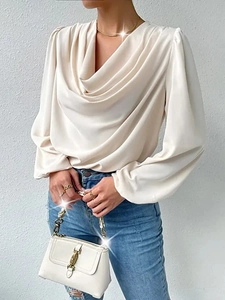Detail of elegant ivory satin blouse showing the draped V-neck and silky fabric texture