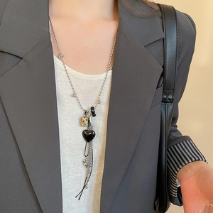 Dettaglio della collana argentata con ciondolo a cuore in pietra quadrata e nappe in metallo