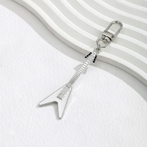 Creative white and silver guitar keychain with metal D-ring clasp on a textured surface