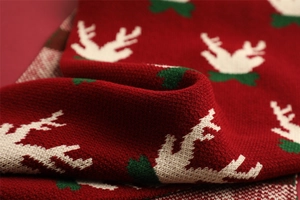 Close-up of red knit scarf featuring white reindeer head and green leaf patterns