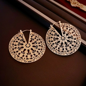 Détail macro de boucles d'oreilles dorées vintage avec motifs floraux ajourés complexes