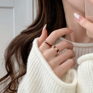 Detail of red enamel heart rings on model's hand with white knitted sweater