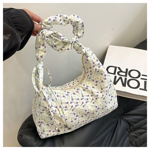 Detail of floral underarm bag with ruffled handle and drawstring in summer style