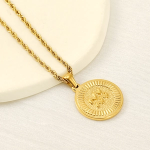 Macro shot of gold Aquarius zodiac pendant with textured edges and fine rope chain