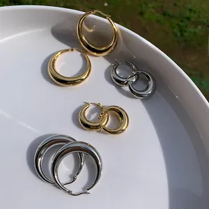 Detailansicht polierter klobiger Creolen in Gold und Silber auf einem weißen Tablett
