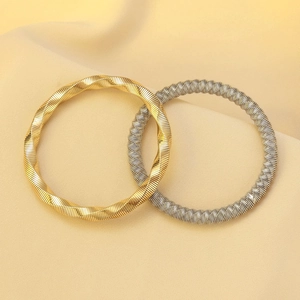 Detailed view of intertwined gold and silver Tubogas spring bracelets on silk background