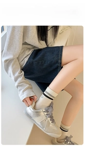 Detail of off-white ribbed socks with stripes, smiley face patch and silver sneakers