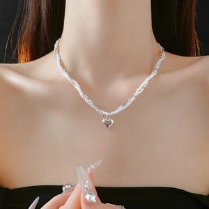 Detail of silver heart pendant with layered white pearl and metal bead chain necklace