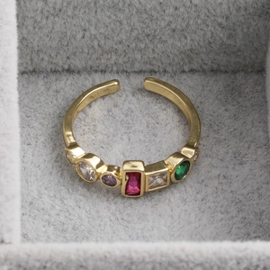 Détail d'une bague dorée ajustable avec pierres en zircon colorées en boîte à bijoux