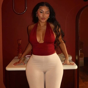 Detail of dark red deep V-neck halter top paired with high-waisted beige pants
