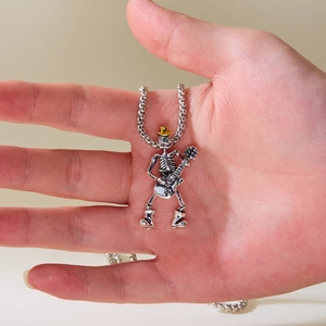 Gros plan d'un pendentif crâne punk jouant de la guitare sur une chaîne argentée