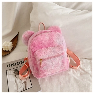 Detailed close-up of a pink plush backpack with bear ears on a cozy white bed background