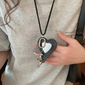 Detail of leather heart pendant with small puppy charm and mirror on a woven strap