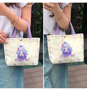 Detail of canvas tote bag showing purple strap handles and anime girl graphic print