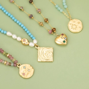 Vintage gold stainless steel necklaces with heart pendants and colorful beads on green surface