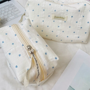 Detailed view of cream-colored cosmetic bags with blue heart patterns and ribbon zipper