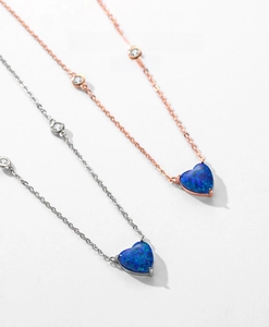 Close-up of heart-shaped opal necklaces in rose gold and silver with cubic zirconia