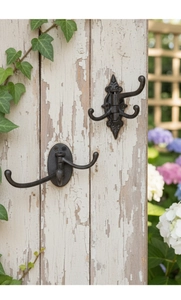 Close-up of vintage cast iron triple swivel hooks on a rustic weathered wood background