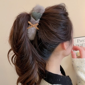 Detail of plush heart hair clip in grey faux fur with a green heart and brown bow