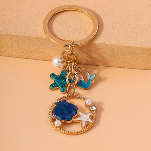 Detailed close-up of golden starfish, seashell, and mermaid tail charms on keychain