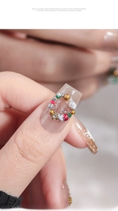 Macro shot of 3D Christmas nail art charms with colorful beads and wreath details
