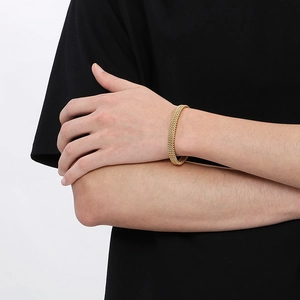 Golden woven stainless steel C-shaped open cuff bracelet shown on a model's wrist